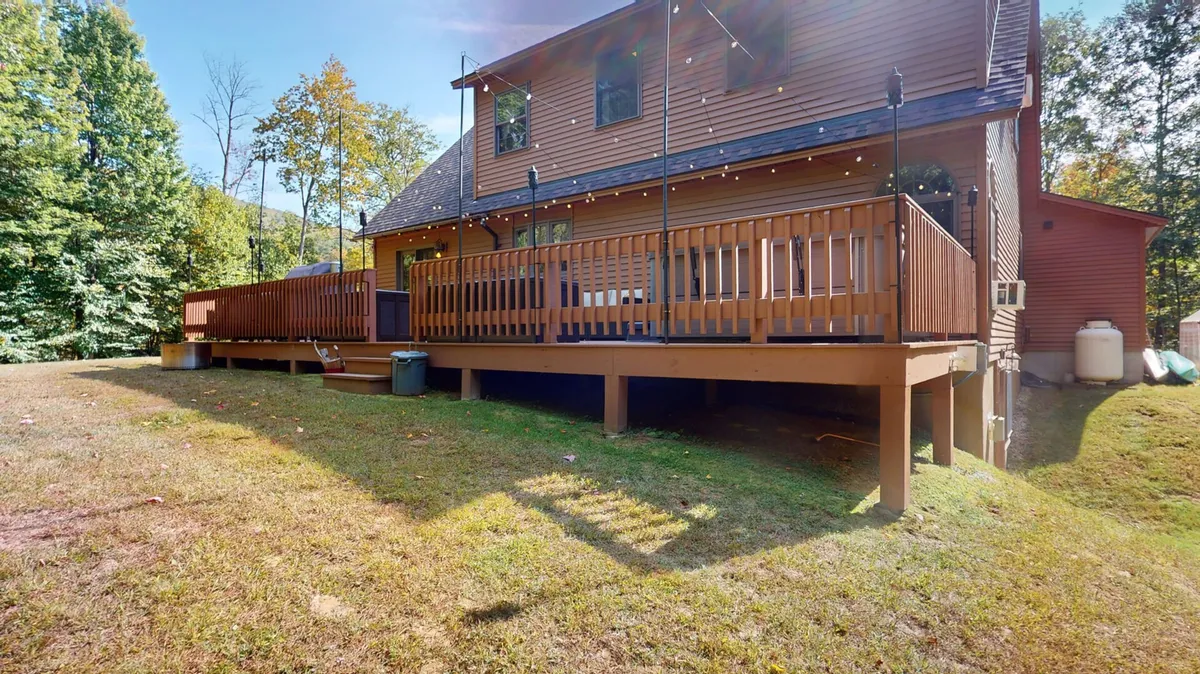 The photograph features a well-appointed deck with wooden railings and a backdrop of dense trees. The scene is set for outdoor dining, relaxing, or evening celebrations, capturing the mood of starlit nights and peaceful mornings in nature.